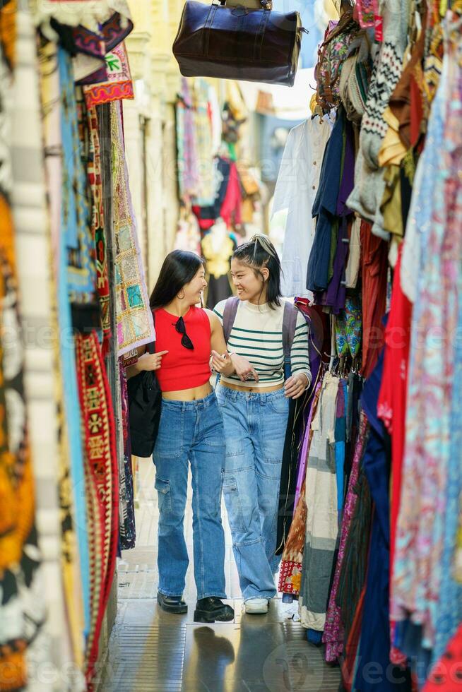 twee Chinese Dames toeristen boodschappen doen kleren in straat bazaar foto