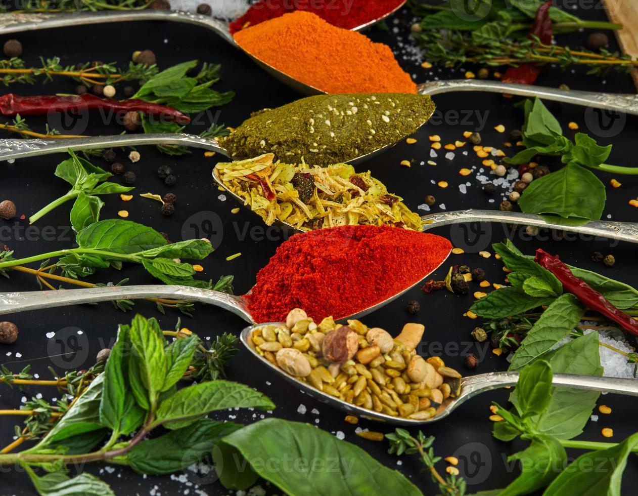 kleurrijke verschillende kruiden en specerijen voor het koken op donkere achtergrond foto