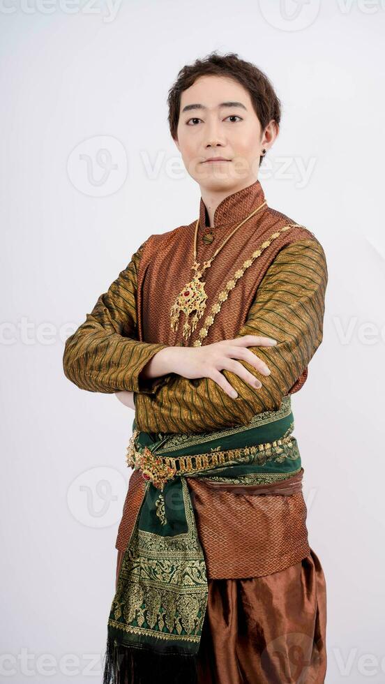 luxe portret van een mooi Thais Mens in traditioneel Thais kostuum staan met armen gekruiste geïsoleerd Aan wit achtergrond foto