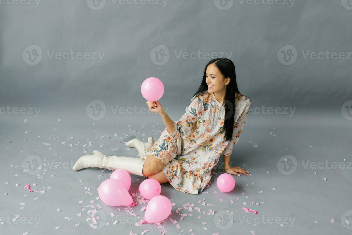 een afbeelding van een vrolijk vrouw wie voelt heel Vrolijk, Holding een roze ballon en lachend, poseren in de buurt ballonnen foto