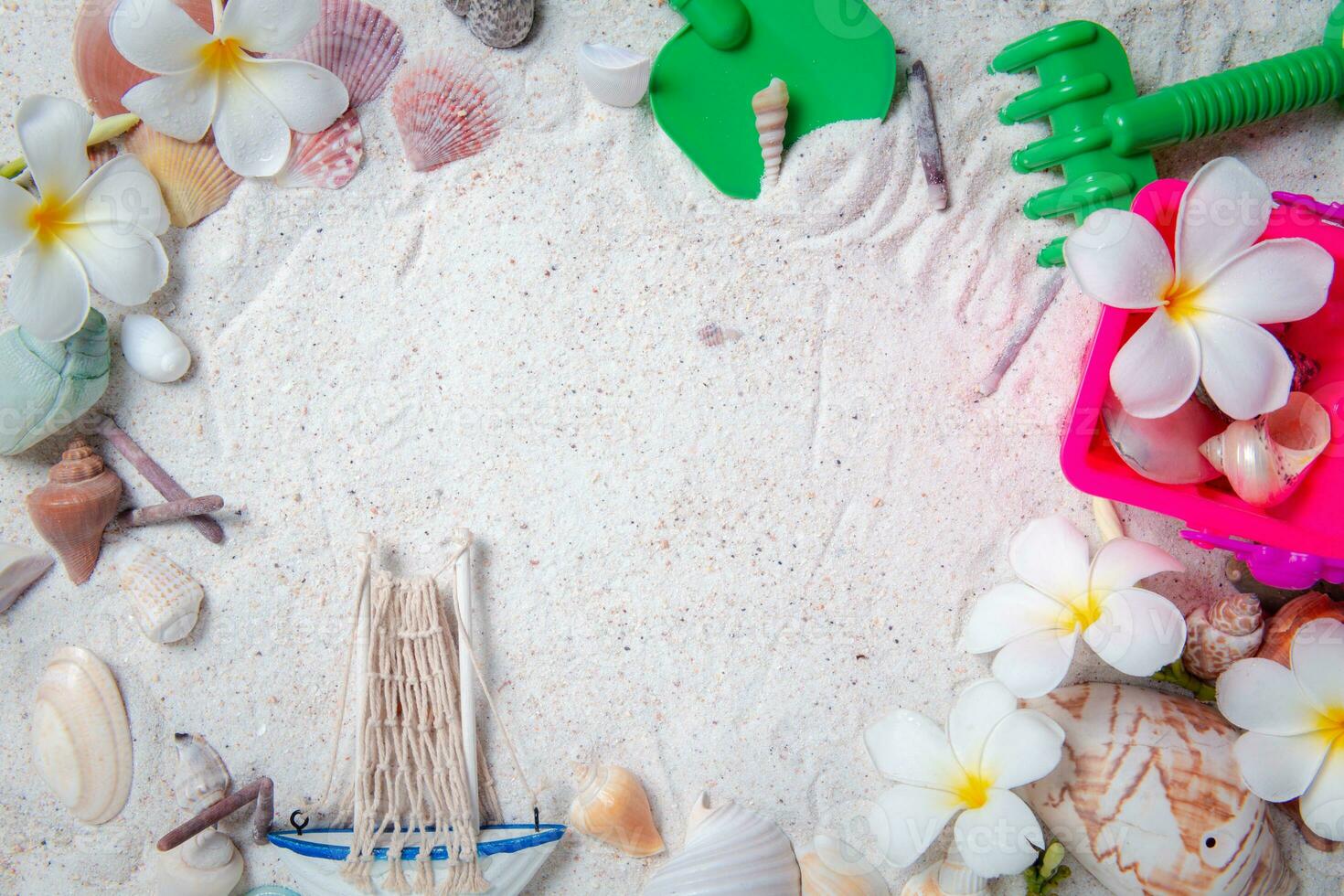 speelgoed kind met zee schelpen en plumeria bloemen Aan zand achtergrond foto
