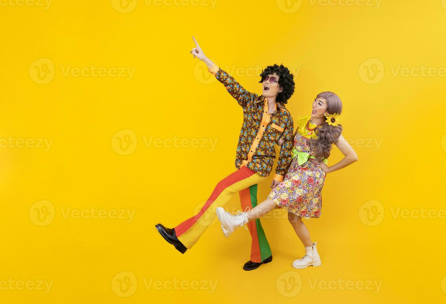 Aziatisch hippie paar jurk in 80s wijnoogst mode met kleurrijk retro kleding terwijl dansen samen geïsoleerd Aan geel achtergrond voor luxe kleding partij en knal cultuur concept foto