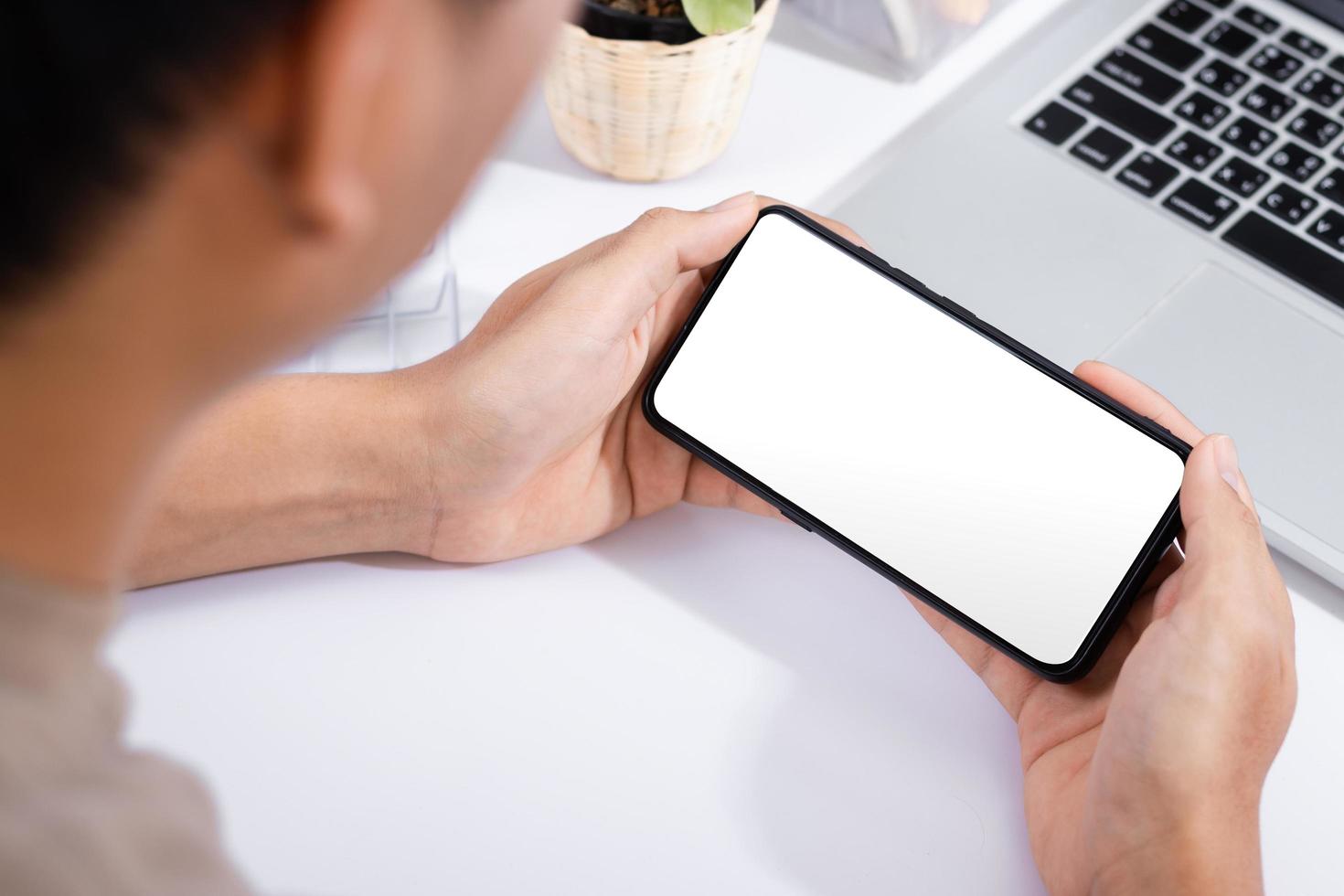 man met een smartphone leeg scherm mock-up op het witte bureau white foto