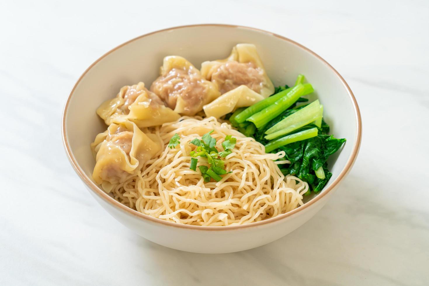 gedroogde eiernoedels met wonton van varkensvlees of dumplings van varkensvlees zonder soep - Aziatisch eten foto