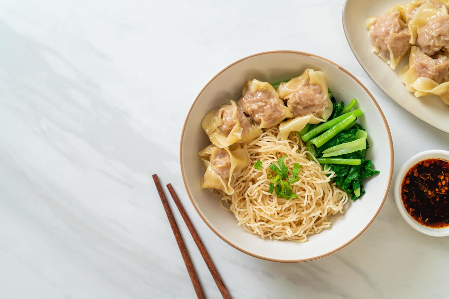 gedroogde eiernoedels met wonton van varkensvlees of dumplings van varkensvlees zonder soep - Aziatisch eten foto