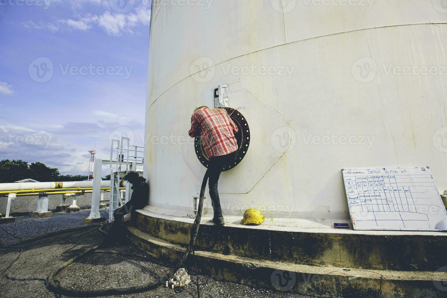 mannetje arbeider in de tank koolstof chemisch olie koppel Oppervlakte beperkt ruimte. foto