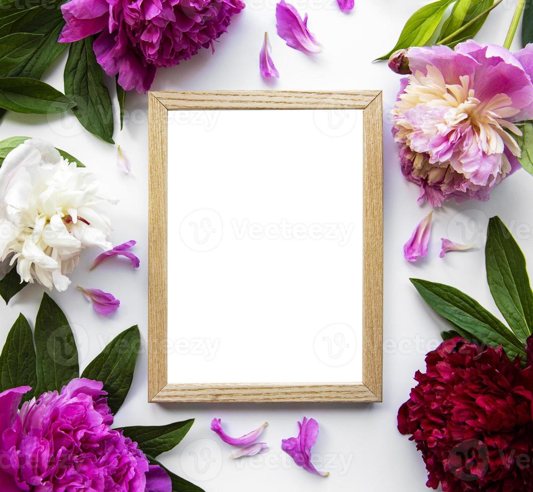 houten frame omgeven door mooie roze pioenrozen op een witte achtergrond foto