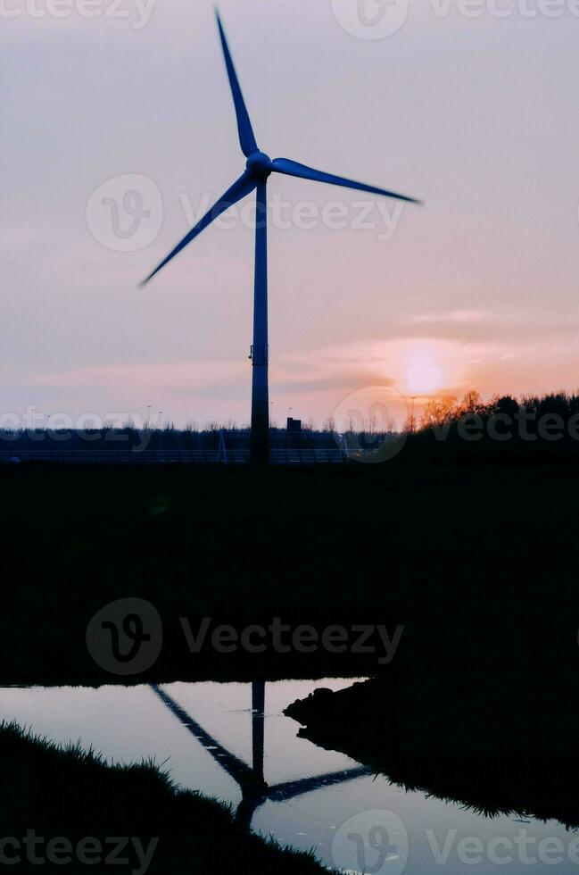 modern windmolen staan reflecterend Aan de water in de Nederland foto