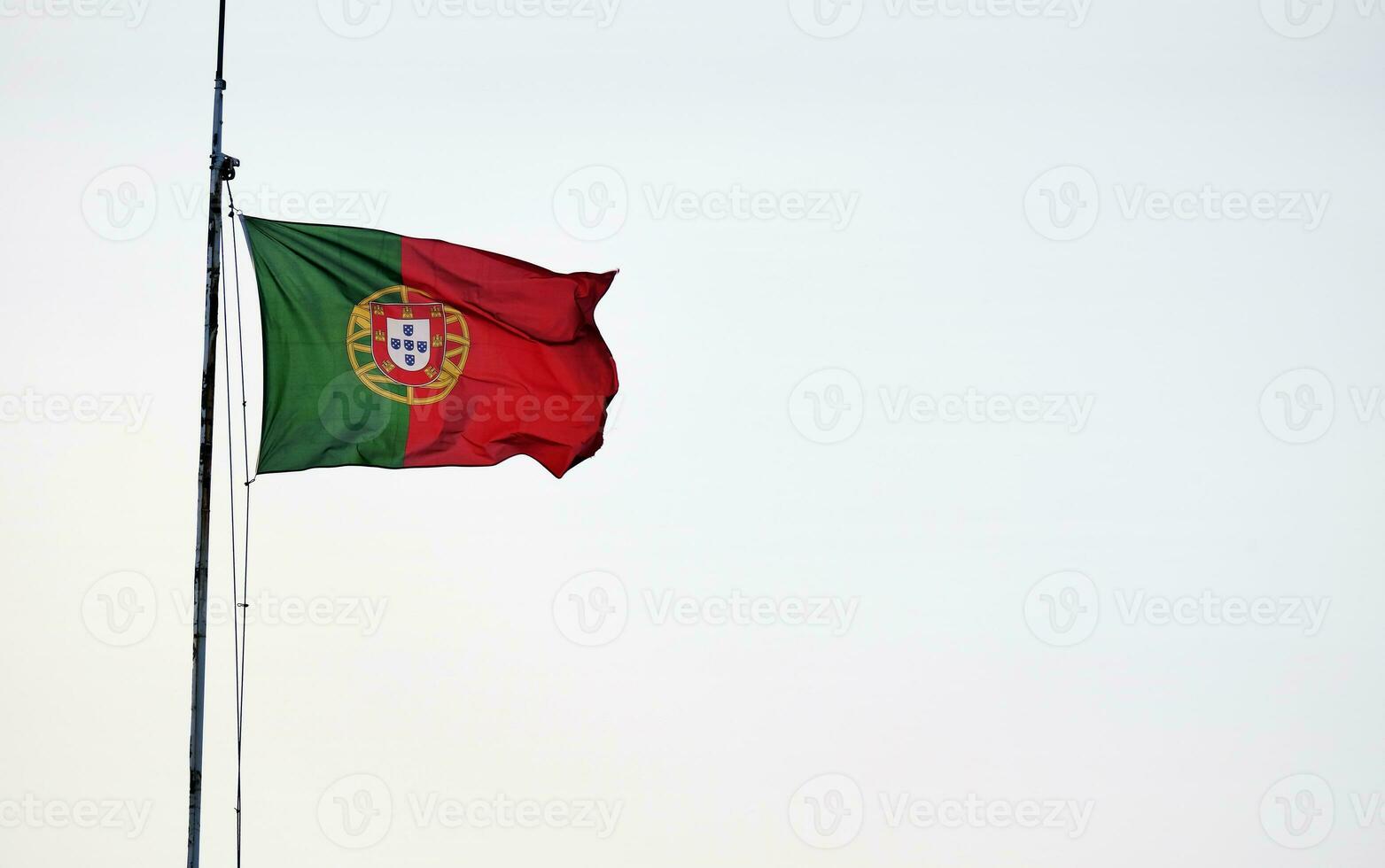 Portugees vlag golvend in de wind tegen een Doorzichtig lucht foto