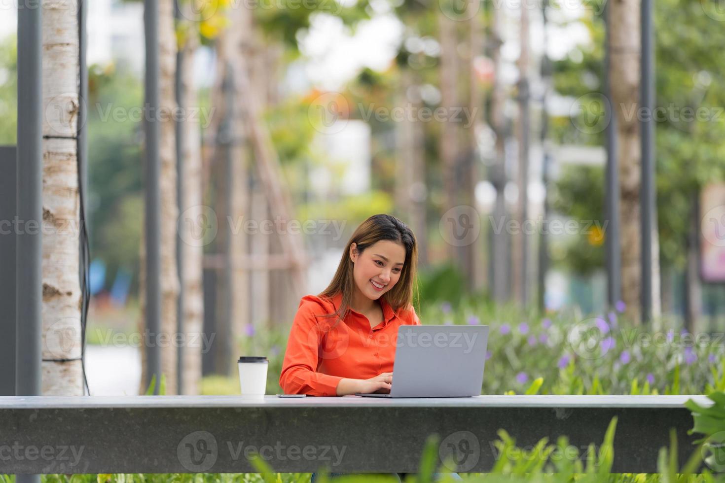 mooie jonge vrouw die laptop gebruikt die bij coffeeshoppark zit foto