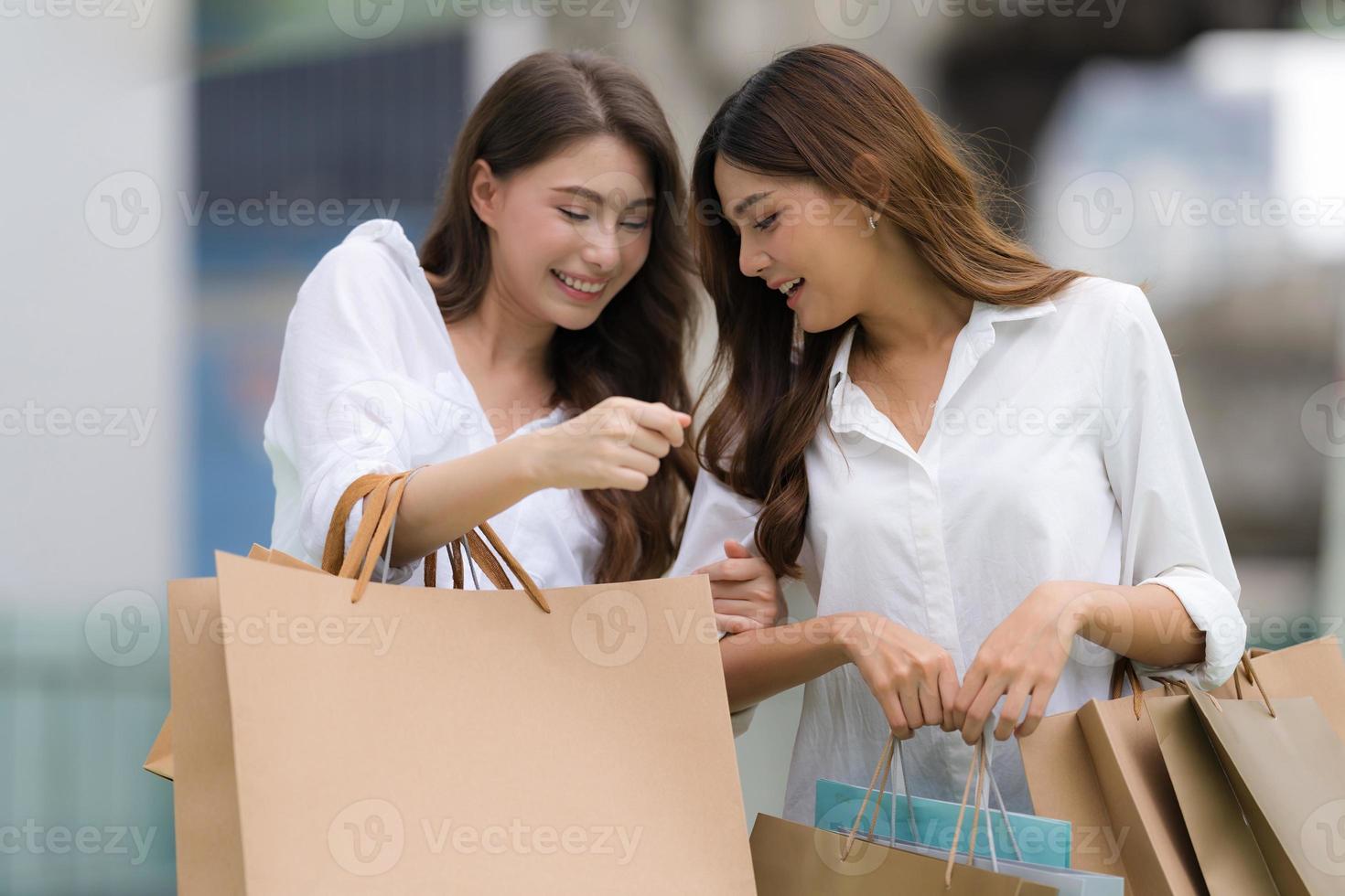 gelukkige vrienden winkelen twee jonge vrouwen houden boodschappentassen vast foto