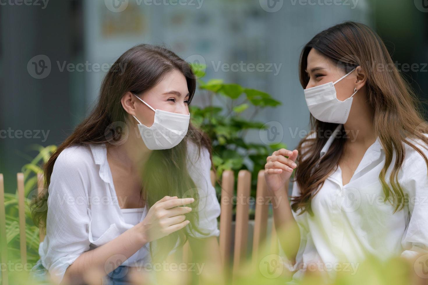 gelukkige twee jonge vrouw met een smileygezicht met een gezichtsmasker dat beschermend praat en lacht foto