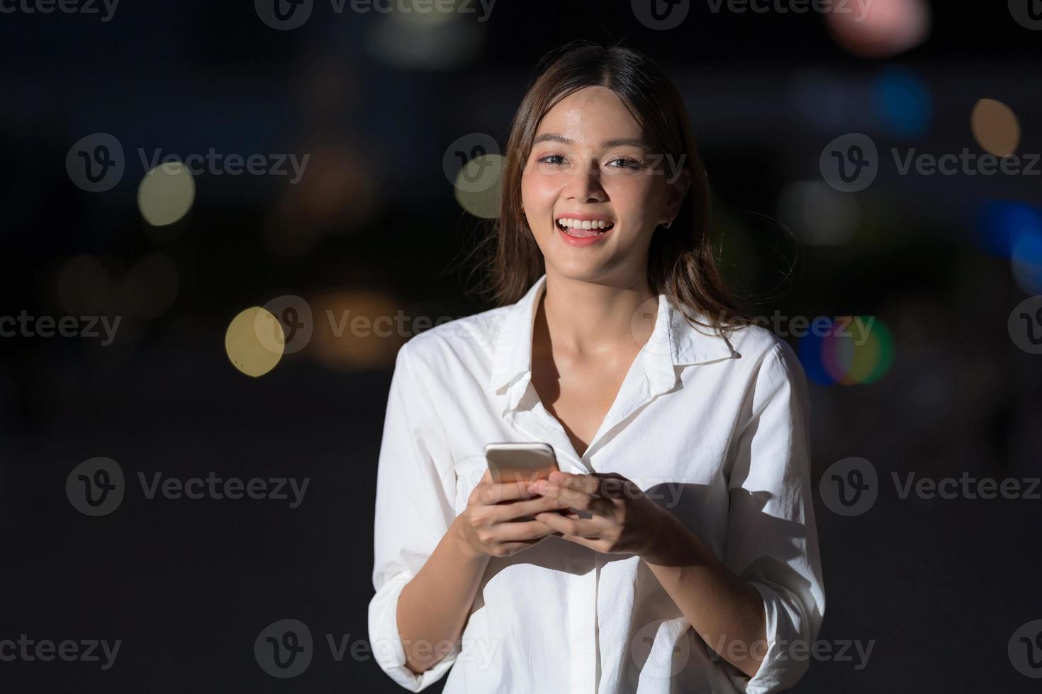 buitenshuis portret van jonge vrouw met smileygezicht met behulp van een telefoon loopt in een stad foto