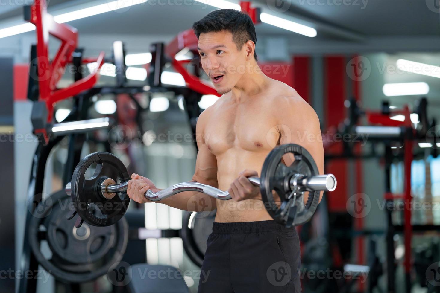 sportieve man traint met een zware barbell in de sportschool foto