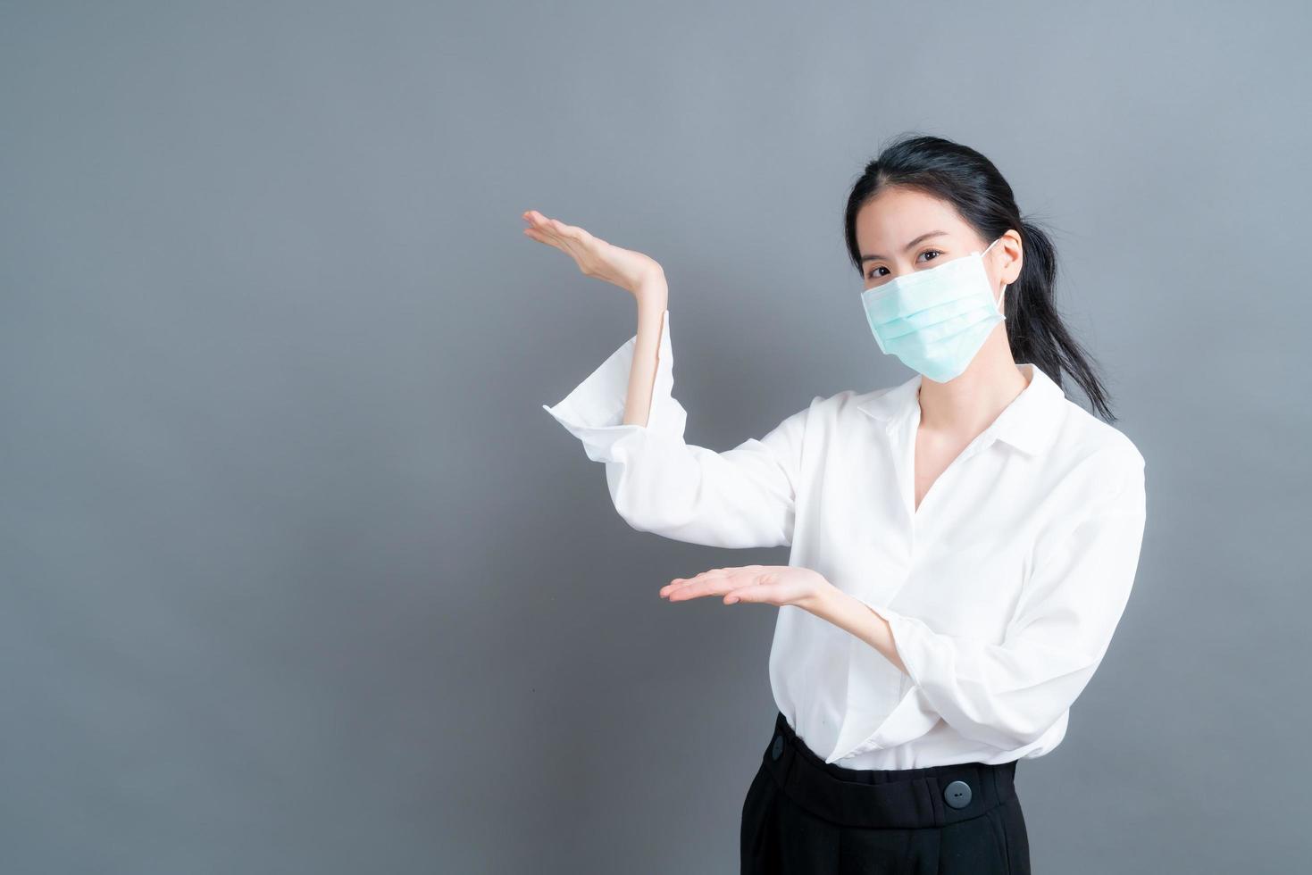 aziatische vrouw die een medisch gezichtsmasker draagt, beschermt filterstof en covid 19 met handpresentatie foto