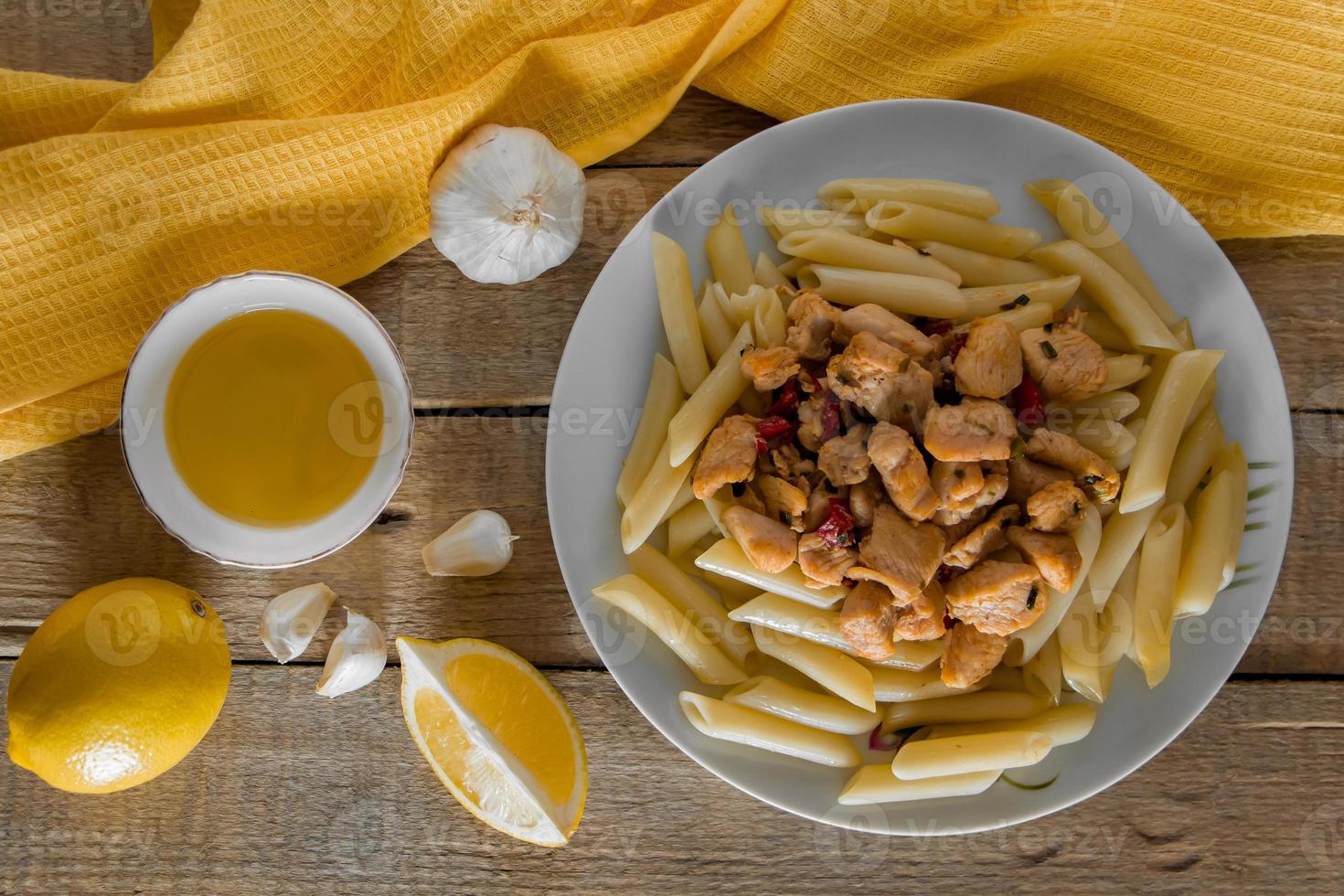 penne pasta met kip in een romige saus op een lichte houten ondergrond foto