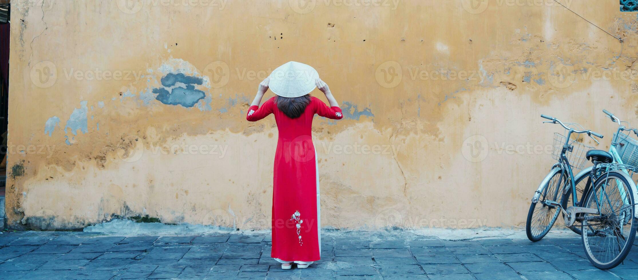 gelukkig vrouw vervelend oa dai Vietnamees jurk en hoed, reiziger bezienswaardigheden bekijken Bij Hoi een oude stad- in centraal Vietnam. mijlpaal en populair voor toerist attracties. Vietnam en zuidoosten reizen concept foto