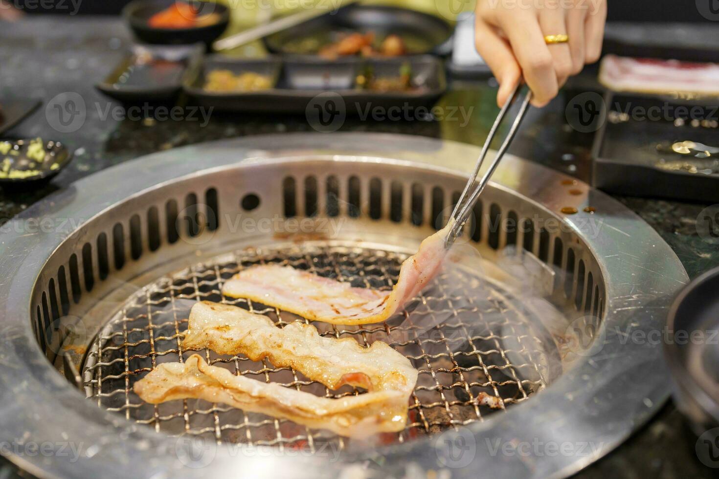 hand- grillen vlees varkensvlees Aan fornuis dienen in restaurant. Japans voedsel en Koreaans bbq traditioneel stijl foto