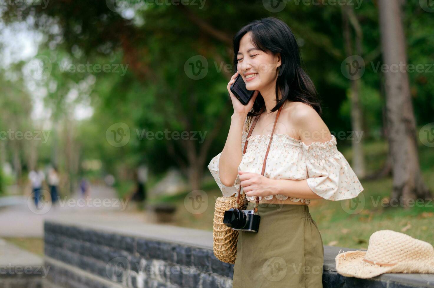 portret van Aziatisch jong vrouw reiziger met het weven hoed, mand, mobiel telefoon en camera Aan groen openbaar park achtergrond. reis reis levensstijl, wereld reizen ontdekkingsreiziger of Azië zomer toerisme concept. foto