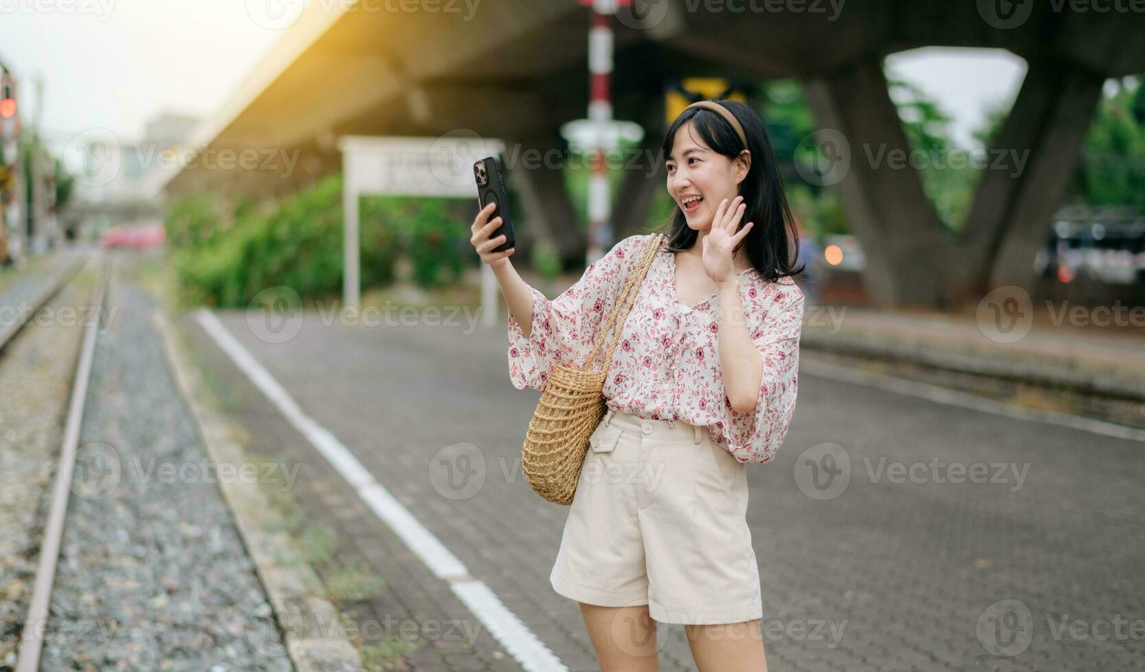 Aziatisch jong vrouw reiziger met het weven mand gebruik makend van een mobiel telefoon naast spoorweg trein station in Bangkok. reis reis levensstijl, wereld reizen ontdekkingsreiziger of Azië zomer toerisme concept. foto