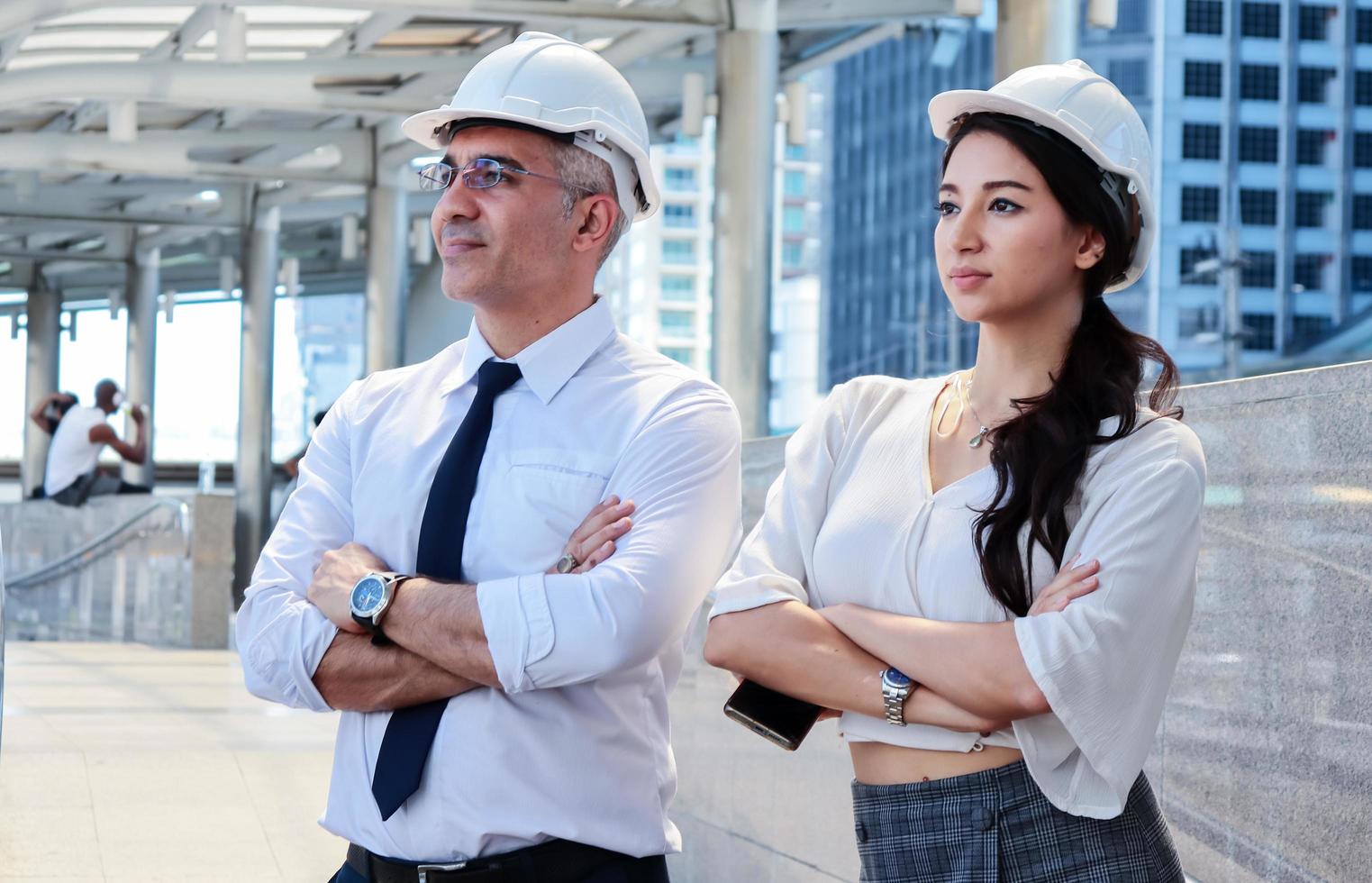 man en vrouw ingenieurs inspecteren de site buiten bouwprojecten in de moderne binnenstad ingenieurs dragen witte veiligheidshelmen voor de veiligheid foto