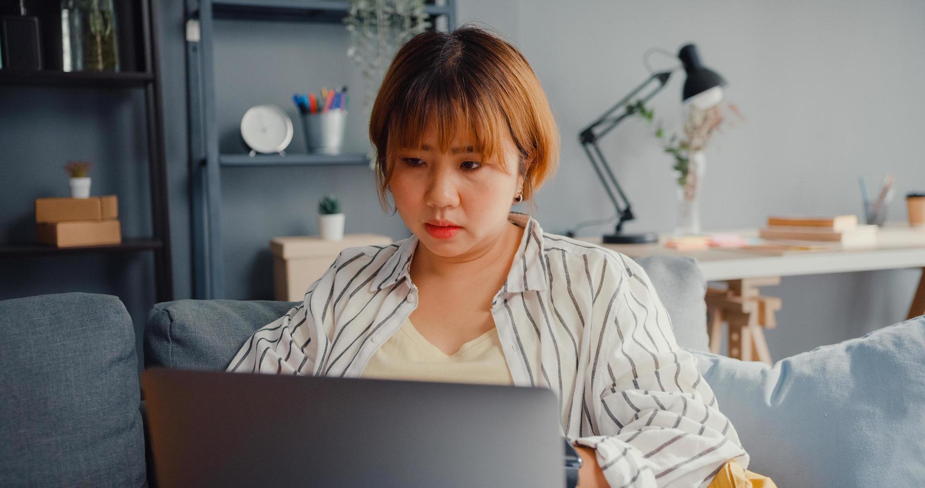 freelance aziatische dame voelt hoofdpijn terwijl ze op de bank zit met laptop online leer in de woonkamer thuis at foto