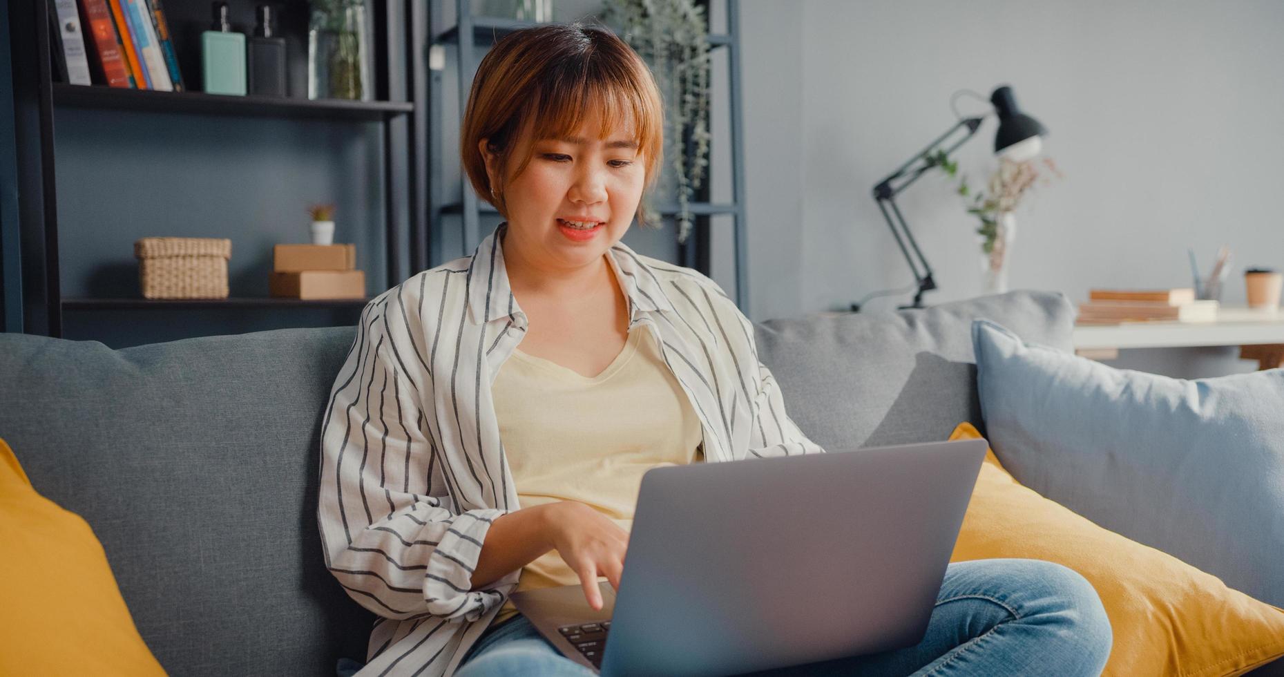 freelance azië dame vrijetijdskleding met behulp van laptop online leren in de woonkamer thuis foto