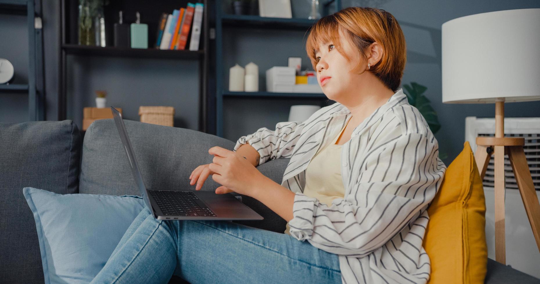 freelance azië dame vrijetijdskleding met behulp van laptop online leren in de woonkamer thuis foto