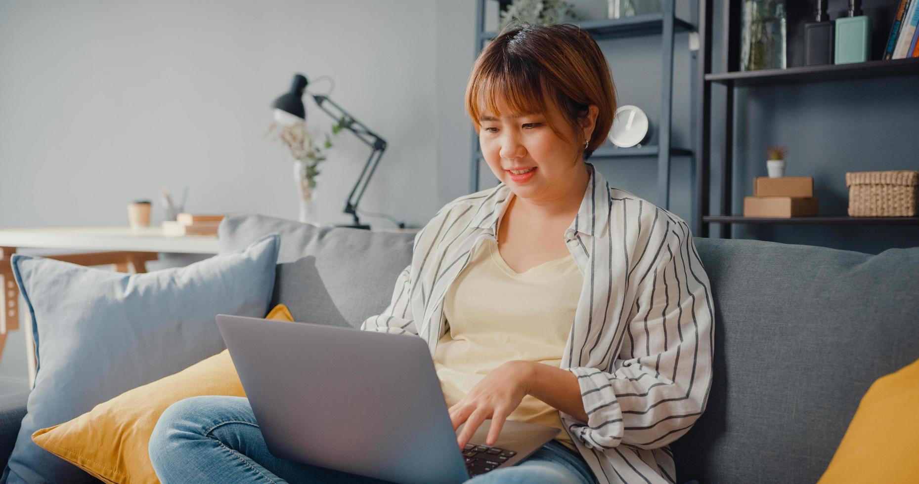 freelance azië dame vrijetijdskleding met behulp van laptop online leren in de woonkamer thuis foto