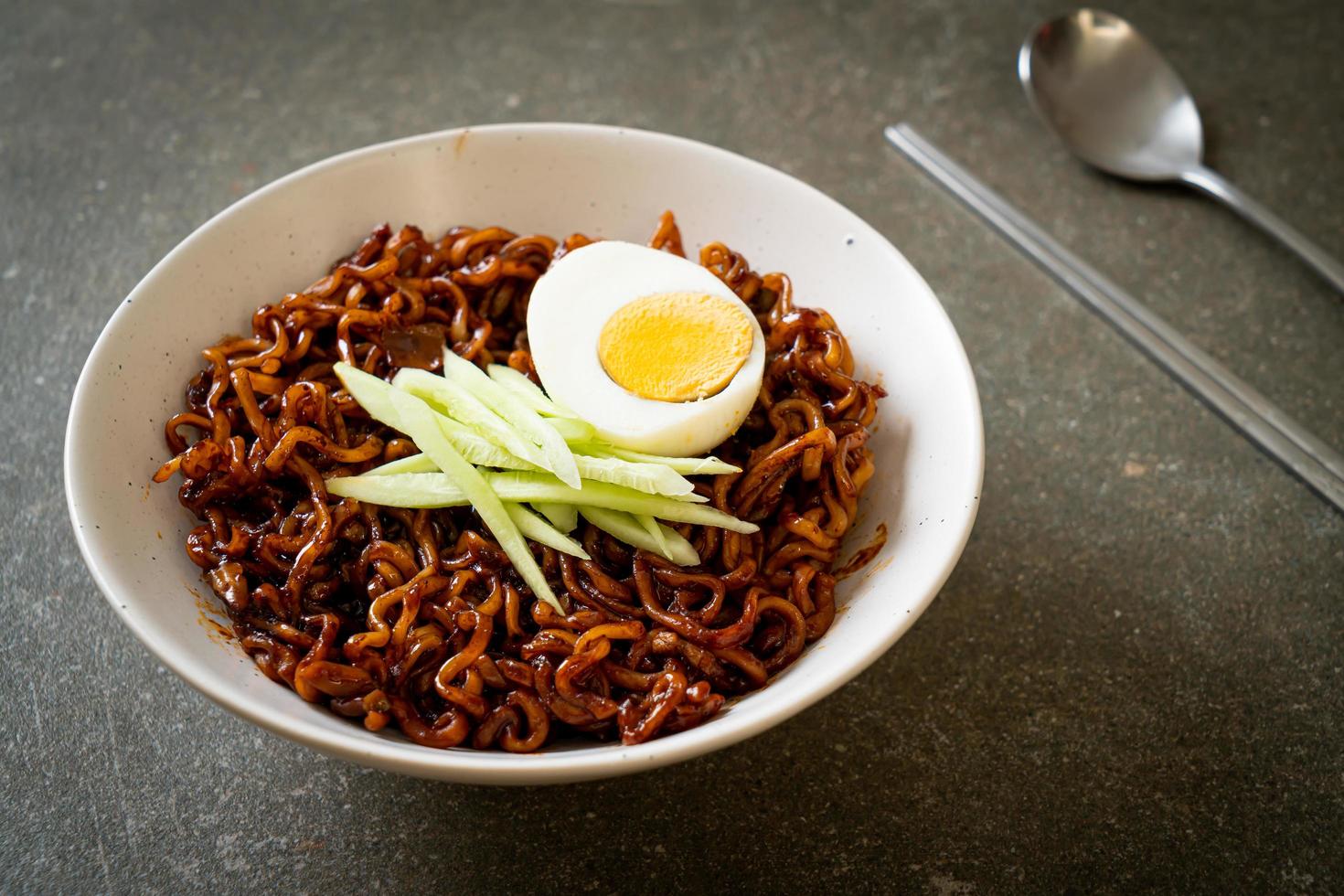 Koreaanse instant noedels met zwarte bonensaus gegarneerd met komkommer en gekookt ei, jjajangmyeon - koreaanse voedselstijl foto