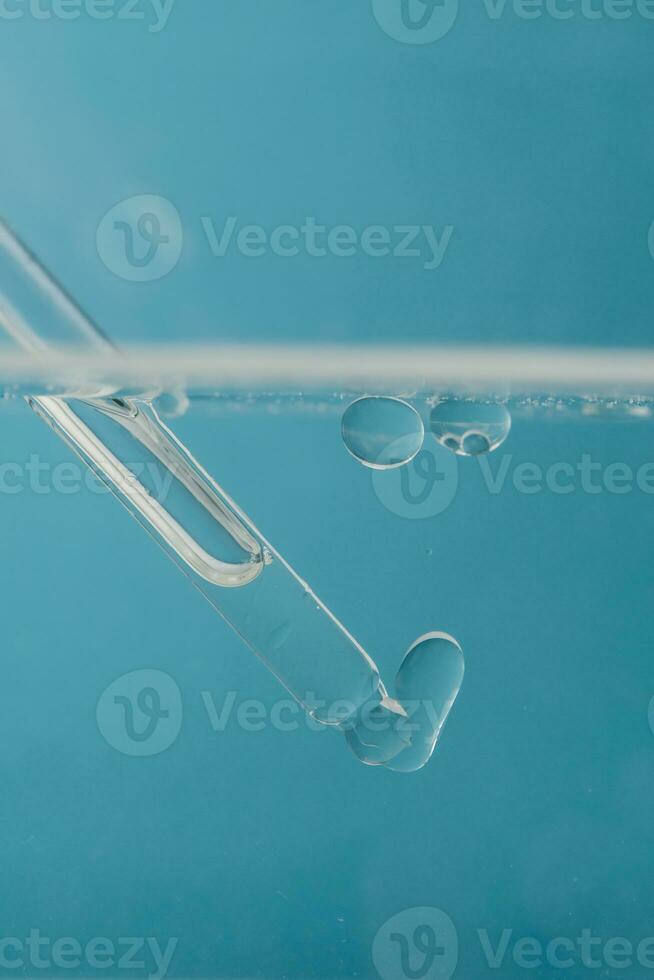 pipet met kunstmatig Product in water met bubbels. foto