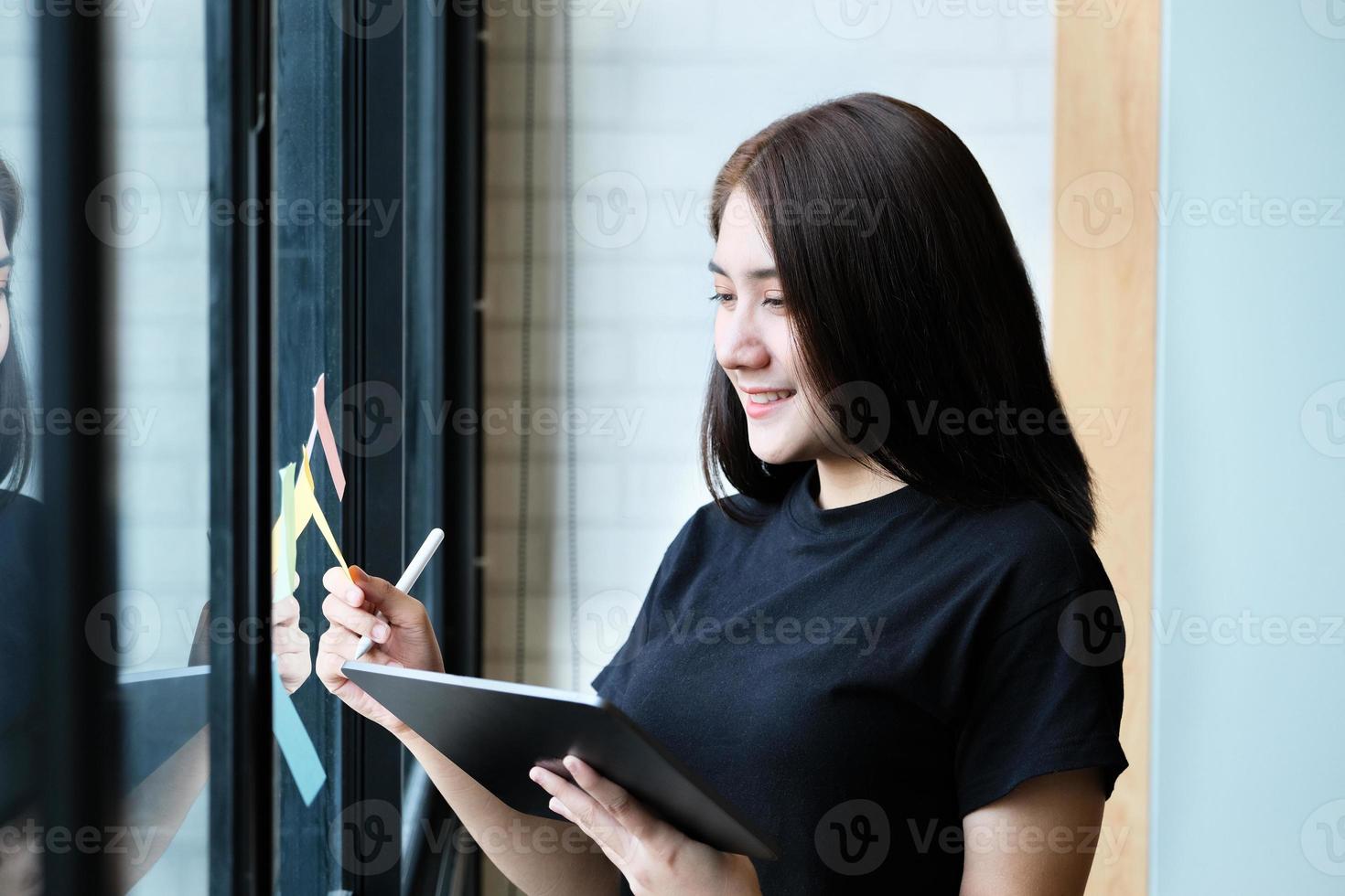 een vrouwelijke bedrijfsmedewerker gebruikt een tablet en een notitieblok om de bedrijfsbudgetten te analyseren foto