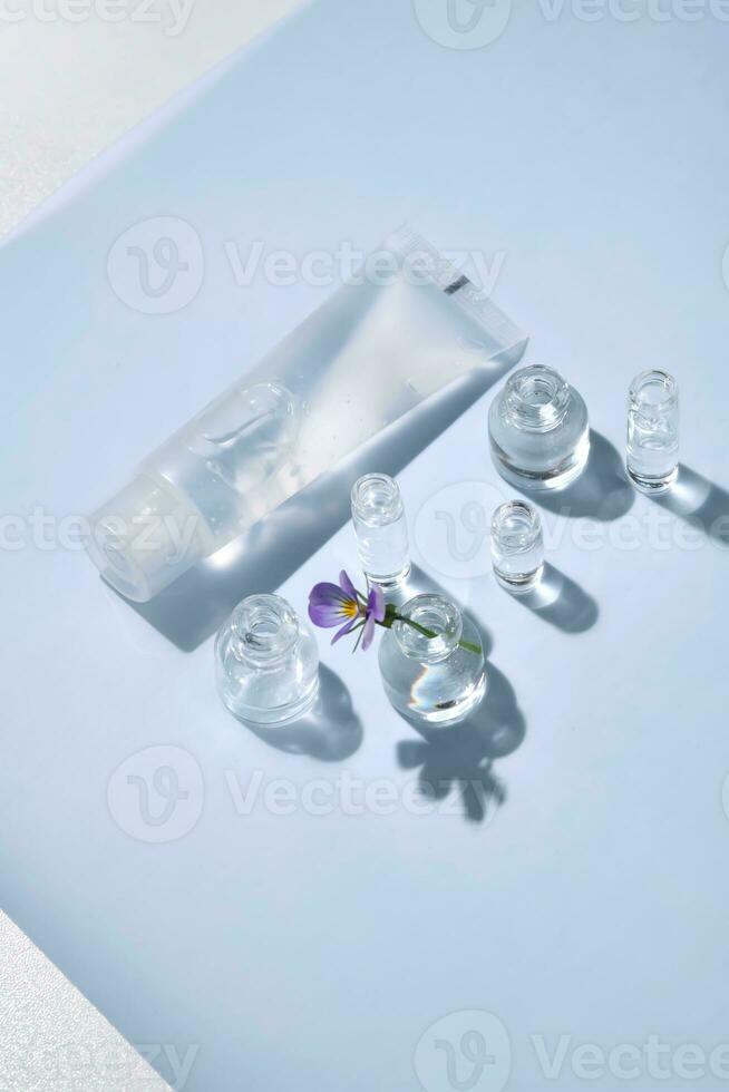 transparant fles van kunstmatig gel Aan een blauw achtergrond met klein flessen van water. foto