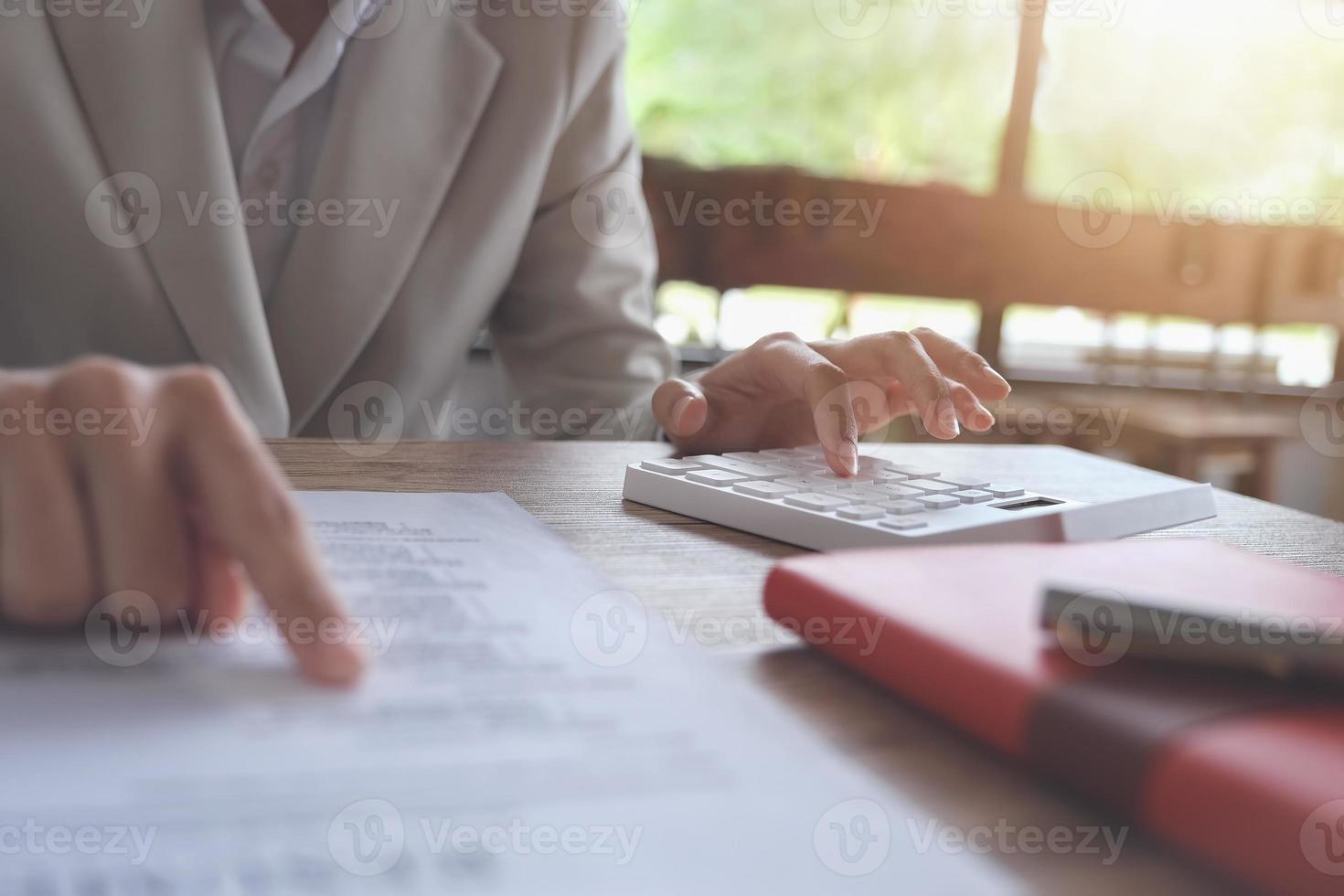 zakenman die rekenmachine gebruikt om budget en leenpapieren op kantoor te berekenen foto
