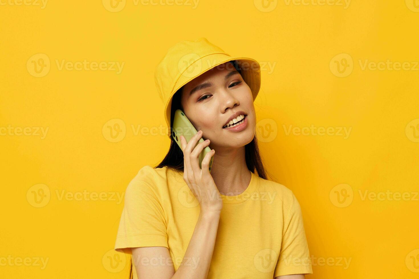 vrouw met Aziatisch uiterlijk pratend Aan de telefoon poseren mode geel achtergrond ongewijzigd foto