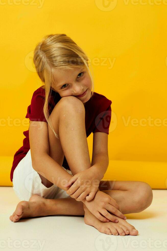 weinig meisje zittend Aan de verdieping geel achtergrond emoties foto