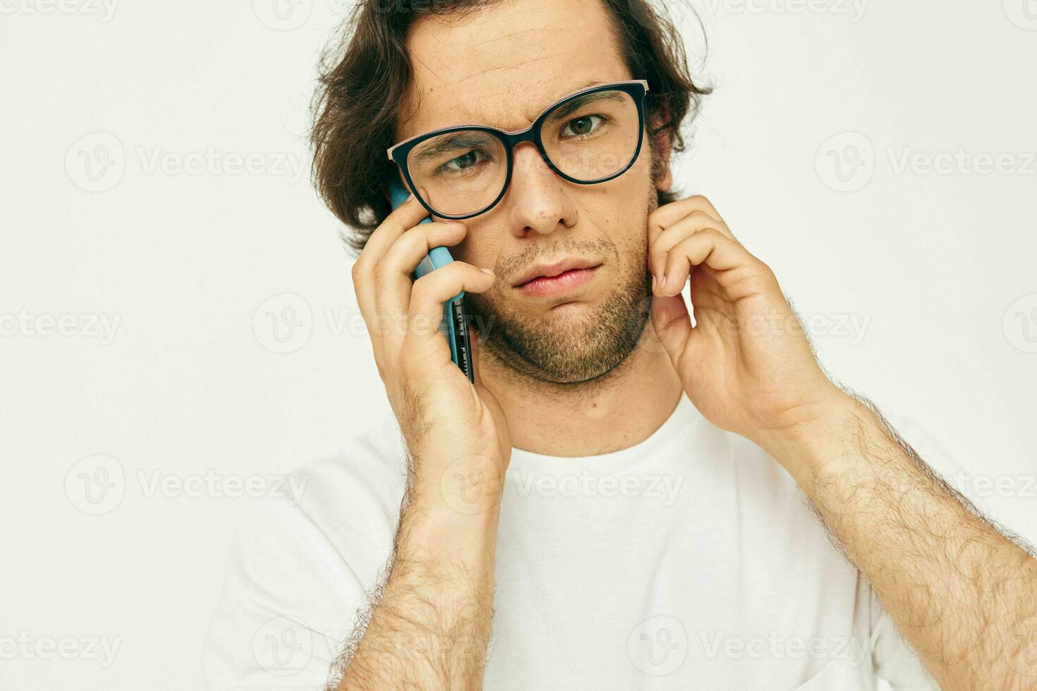 aantrekkelijk Mens in een wit t-shirt communicatie door telefoon licht achtergrond foto