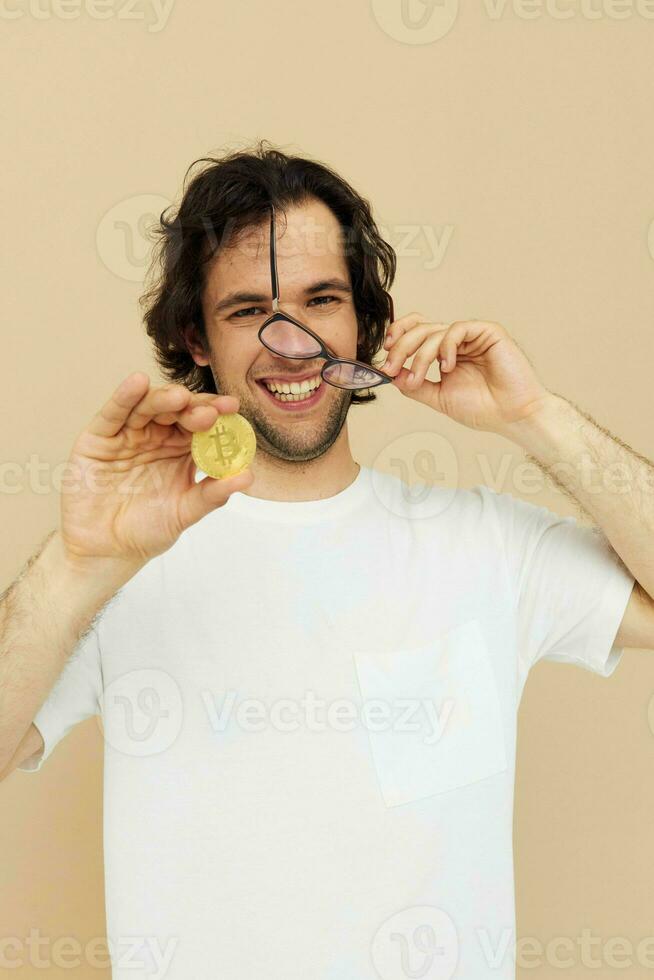 aantrekkelijk Mens in een wit t-shirt met bitcoin cryptogeld beige achtergrond foto
