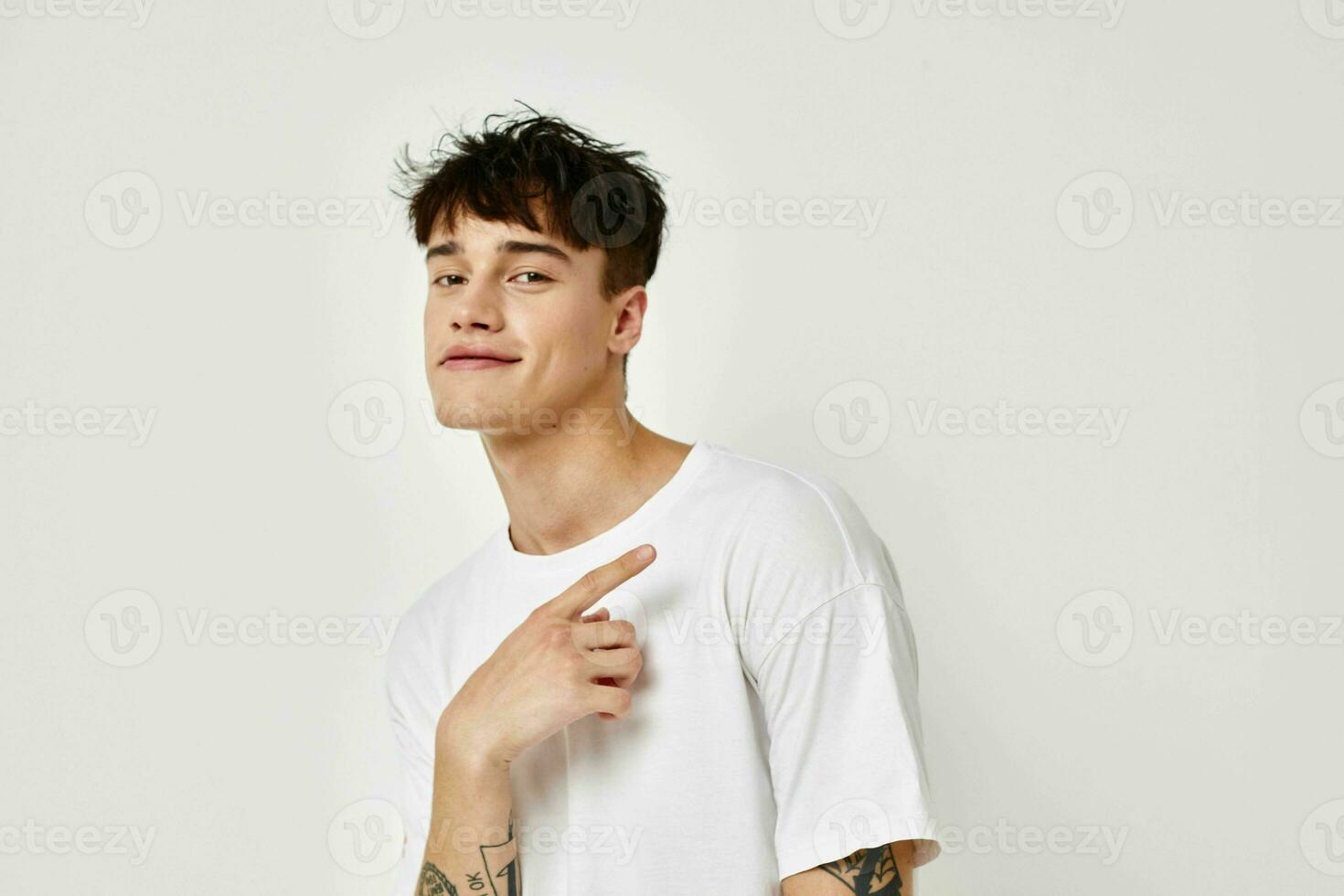 portret van een jong Mens modern jeugd stijl wit t-shirt tatoeëren Aan de arm licht achtergrond ongewijzigd foto