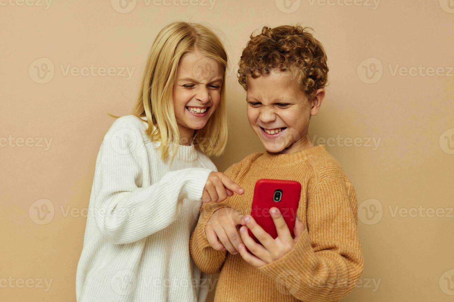 foto van twee kinderen in truien poseren voor pret met telefoon geïsoleerd achtergrond