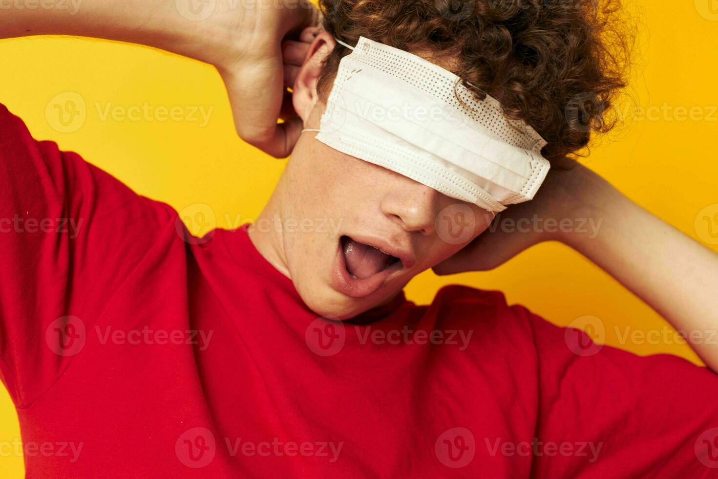 vent met rood gekruld haar- vervelend een rood t-shirt medisch masker Aan de gezicht poseren levensstijl ongewijzigd foto