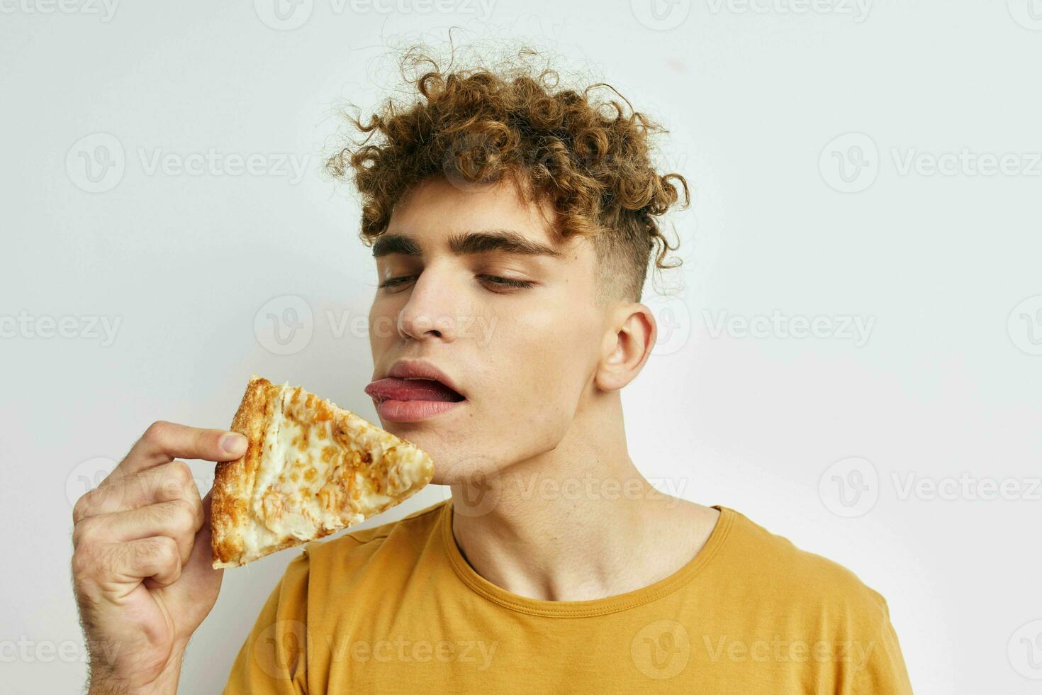 knap vent in een geel t-shirt aan het eten pizza geïsoleerd achtergrond foto