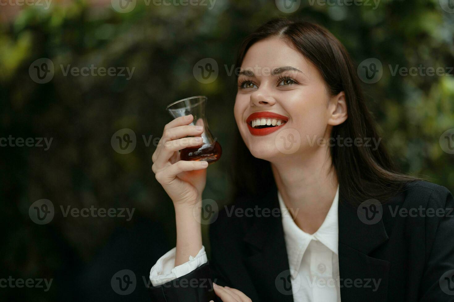 vrouw glimlach met tanden drinken thee in een cafe van een Turks glas mok Aan de straat, voorjaar reis, stad breken foto