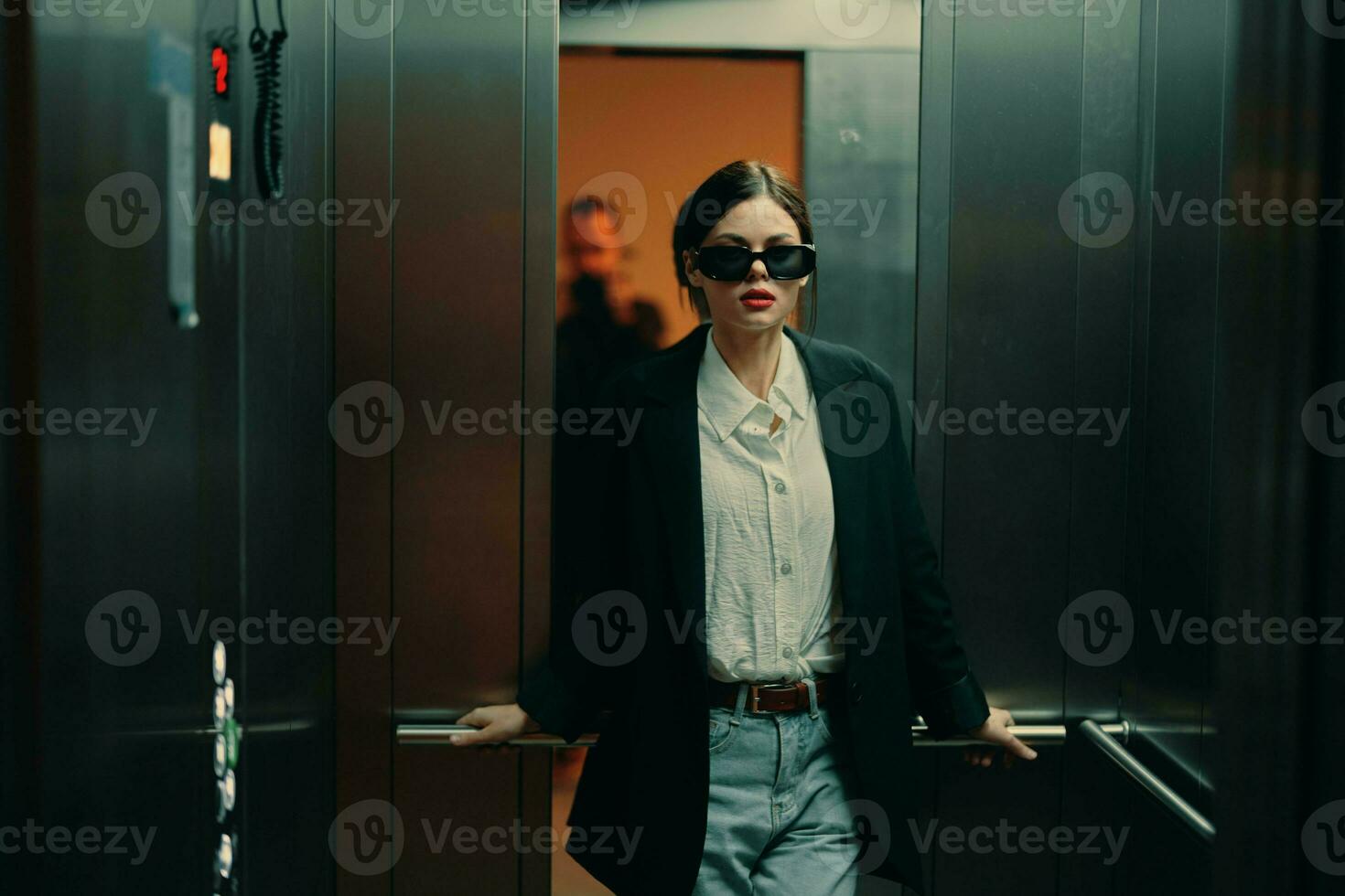 elegant vrouw in zwart jasje en zonnebril poseren in lift, mode model, donker filmische licht en kleur, aantrekkingskracht wijnoogst foto