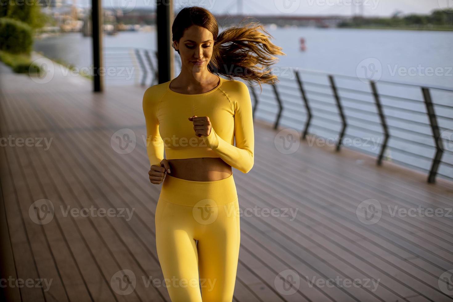 jonge vrouw die hardloopoefeningen doet aan de rivierpromenade foto