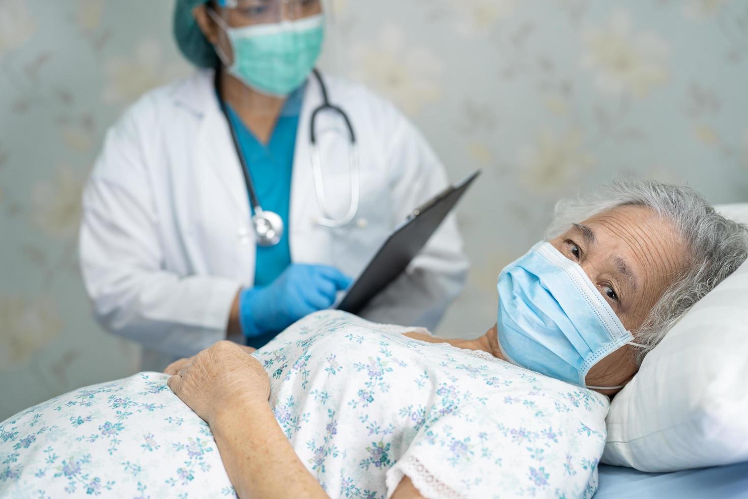 arts die een stethoscoop gebruikt om te controleren Aziatische senior of oudere oude dame vrouw patiënt draagt een gezichtsmasker in het ziekenhuis voor bescherming van infectie covid 19 coronavirus foto