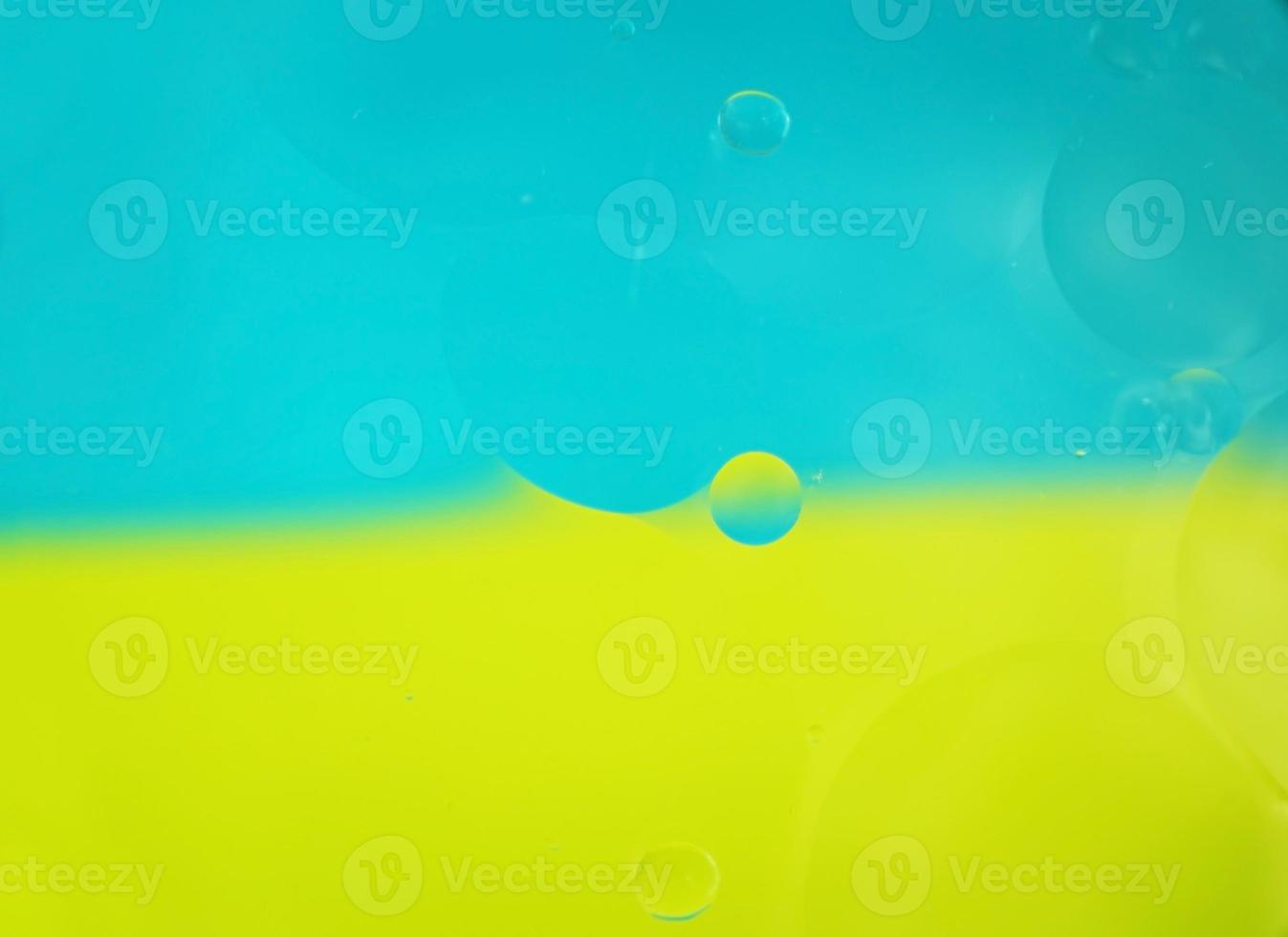 een mooie en kleurrijke macro van oliebellen op water met twee kleuren als achtergrond met hoog contrast, blauw en geel foto