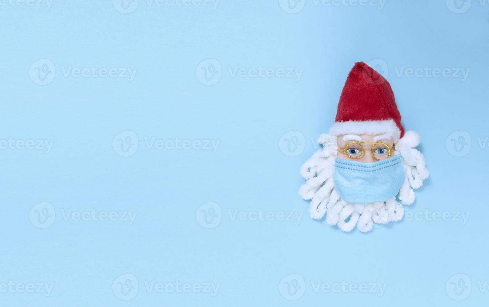 kerstman met medisch masker op een blauw papier. eenvoudig plat leggen met kopieerruimte. foto