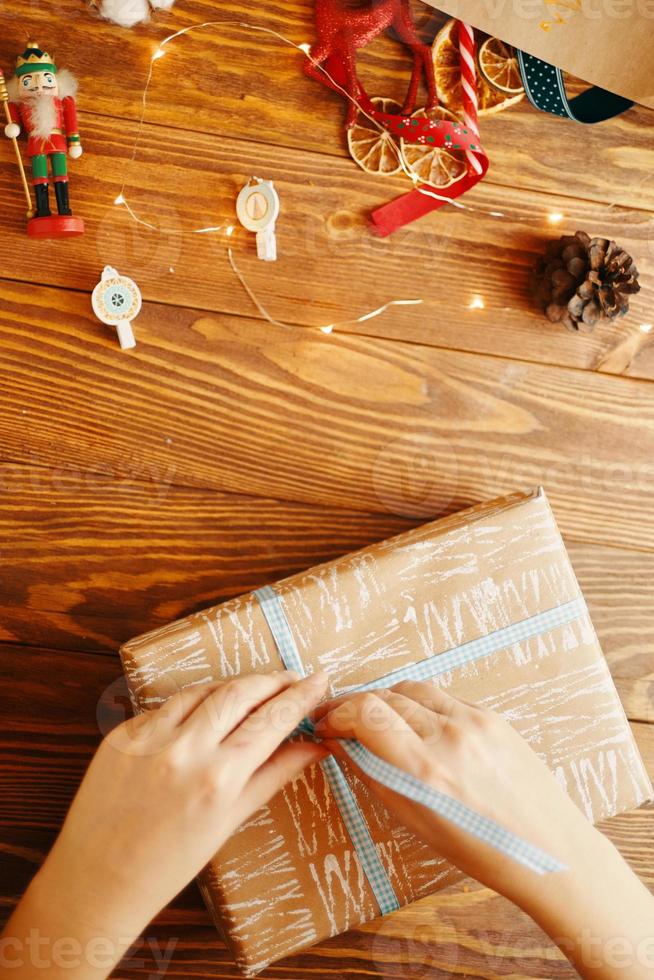 vrouwenhanden binden lint op kerstcadeau foto