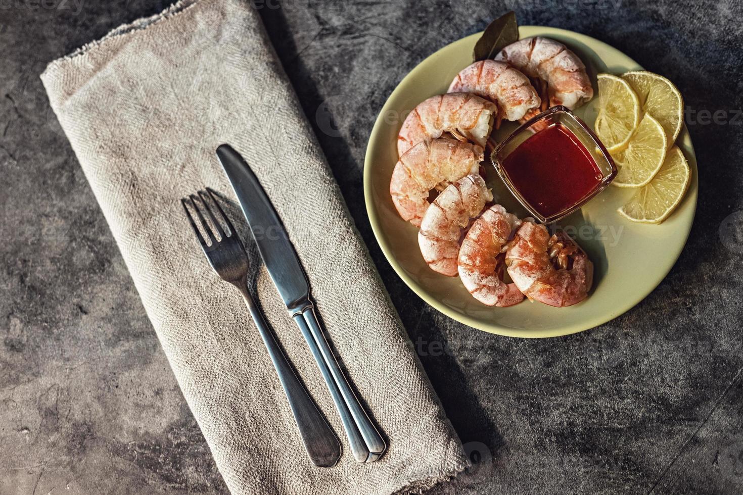 op een groen bord, gamba's met bosbessensaus en citroen. bestek op een linnen servet. het concept van gezond eten foto